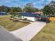 Charming single-story home featuring a gravel driveway, carport, manicured lawn, and modern landscaping at 1423 Palmetto St, New Smyrna Beach, FL 32168