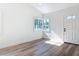 Sunlit living room with wood-look flooring, corner windows, and a bright entryway at 1423 Palmetto St, New Smyrna Beach, FL 32168