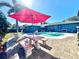 Backyard oasis with red umbrella, table, and kidney pool at 1424 Breaks Way, Port Orange, FL 32127