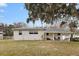 Ranch style home with covered porch and large oak tree at 1596 Elizabeth St, New Smyrna Beach, FL 32168