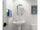 Powder room with pedestal sink, oval mirror, and wood-look floor at 2302 S Atlantic Ave, New Smyrna Beach, FL 32169