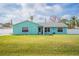 Light teal single story house with a white picket fence and nicely landscaped lawn at 2720 Queen Palm Dr, Edgewater, FL 32141