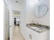 Guest bathroom with granite countertop, white cabinets, and view of kitchen at 434 Bouchelle Dr # 202, New Smyrna Beach, FL 32169