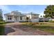 White two-story house with gray metal roof, paved driveway, and landscaped yard at 437 S Peninsula Ave, New Smyrna Beach, FL 32169