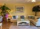 Living room with a white L-shaped sofa, palm tree, and beach artwork at 5300 S Atlantic Ave # 5-206, New Smyrna Beach, FL 32169