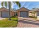 Front view of tan house with gray garage doors and landscaping at 108 Tuscany Villas Dr # 108, Edgewater, FL 32141