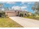 Tan house exterior with a two-car garage and landscaped front yard at 1155 Kilkenny Ln, Ormond Beach, FL 32174