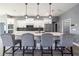 Modern kitchen island with seating and gray fabric chairs, white cabinets, and pendant lighting at 18459 Sw 66Th Loop, Dunnellon, FL 34432