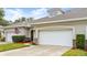 Tan two-story house with white garage door and landscaping at 1957 Turnbull Lakes Dr, New Smyrna Beach, FL 32168