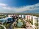 Aerial view of community tennis courts, lush green landscaping, and colorful condominiums at 2 Riverwalk Dr # 402, New Smyrna Beach, FL 32169