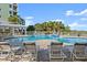 Exterior view of a pool with lounge chairs, palm trees, and a glimpse of a nearby pond at 2 Riverwalk Dr # 402, New Smyrna Beach, FL 32169