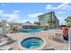 Exterior view of a pool and hot tub with palm trees and a grilling area at 2 Riverwalk Dr # 402, New Smyrna Beach, FL 32169