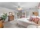 Bright bedroom features white walls and neutral carpet, ceiling fan, dresser, and a peek into the en suite bathroom at 2232 Swoope Dr, New Smyrna Beach, FL 32168