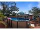 Backyard featuring an above-ground pool, wooden deck, shed, and mature trees under a blue sky at 229 Columbus Ave, Daytona Beach, FL 32118