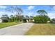 View of home's exterior, with a long curved driveway, lawn, and mature landscaping at 2813 Sabal Palm Dr, Edgewater, FL 32141