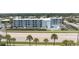 Birds eye view of a multi-story building featuring a pool, parking, palm trees, and nearby highway at 3700 S Atlantic Ave # 108, New Smyrna Beach, FL 32169