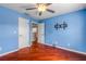 A cozy blue bedroom features hardwood floors, a ceiling fan, and an open doorway at 454 Venetian Villa Dr, New Smyrna Beach, FL 32168