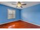 Inviting blue bedroom with a ceiling fan, a window and beautiful hardwood floors at 454 Venetian Villa Dr, New Smyrna Beach, FL 32168