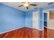 A blue bedroom featuring hardwood floors, a ceiling fan, and an open doorway at 454 Venetian Villa Dr, New Smyrna Beach, FL 32168