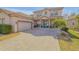 Charming two-story home showcasing a paved driveway, two-car garage, and manicured landscaping at 454 Venetian Villa Dr, New Smyrna Beach, FL 32168