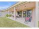 Wide view of the covered patio, complete with outdoor dining set, lounge chairs, and a manicured lawn at 454 Venetian Villa Dr, New Smyrna Beach, FL 32168