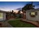 Backyard at sunset featuring a pergola-covered deck, garden shed, lush lawn and tropical landscaping at 4650 Saxon Dr, New Smyrna Beach, FL 32169