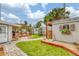 Landscaped backyard featuring a red-decked pergola, garden shed with flower box and brick paver walkway at 4650 Saxon Dr, New Smyrna Beach, FL 32169