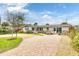 Well-maintained single-story home featuring a brick driveway, lush lawn, and inviting facade at 4650 Saxon Dr, New Smyrna Beach, FL 32169