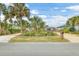 Street view of a charming home with gravel driveway, tropical landscaping, and manicured front yard at 4650 Saxon Dr, New Smyrna Beach, FL 32169