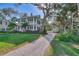 Two-story light blue house with red door, gravel driveway, and mature trees at 504 N Riverside Dr, New Smyrna Beach, FL 32168