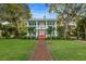 Two-story light blue house with red door, brick pathway, and lush landscaping at 504 N Riverside Dr, New Smyrna Beach, FL 32168