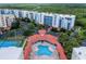 Stunning aerial view of the community pool, tennis courts, and condo buildings surrounded by lush greenery at 5300 S Atlantic Ave # 3-504, New Smyrna Beach, FL 32169