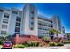 Multi-story building featuring multiple balconies and a manicured landscape with palm trees on a bright, sunny day at 5300 S Atlantic Ave # 3-504, New Smyrna Beach, FL 32169