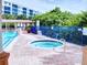 Relaxing community hot tub with a paved deck, surrounded by a blue fence and greenery at 5300 S Atlantic Ave # 3-504, New Smyrna Beach, FL 32169