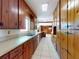 A galley kitchen with wood cabinets, a double-bowl sink, and a white tiled floor that leads into an adjacent room at 634 N Riverside Dr, New Smyrna Beach, FL 32168