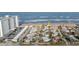 Ocean view of a beach house and tropical landscaping; featuring white sandy beach and a backdrop of modern towers at 8 Ocean Dr, Ormond Beach, FL 32176