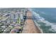 Ocean view of a cute beach house by sandy shoreline and tropical plants near a high-rise building at 8 Ocean Dr, Ormond Beach, FL 32176