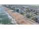 Coastal view of a charming white beach cottage flanked by palm trees near the sandy shoreline and ocean at 8 Ocean Dr, Ormond Beach, FL 32176