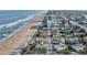 An elevated view showcasing a white beach cottage with palm trees near the sandy shoreline and ocean waves at 8 Ocean Dr, Ormond Beach, FL 32176