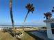 Charming backyard view with a picnic table, palm trees, and ocean in the background at 8 Ocean Dr, Ormond Beach, FL 32176