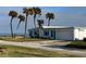 Charming coastal home featuring white siding, blue accents, attached garage, and swaying palm trees at 8 Ocean Dr, Ormond Beach, FL 32176