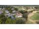 An aerial view shows a home with a screen lanai and a tile roof next to a golf course with mature trees at 958 Beach Fern Ct, New Smyrna Beach, FL 32168