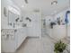 Bright bathroom with double vanities, a soaking tub, neutral tile, and decorative accents at 958 Beach Fern Ct, New Smyrna Beach, FL 32168