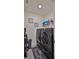 A modern laundry room featuring a front-loading washer and dryer set, shelving, and neutral tile flooring at 114 Sunset Point Dr, Ormond Beach, FL 32174