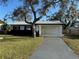 Charming single-story home featuring a metal roof, white siding and a spacious front yard with mature landscaping at 128 Orange Ave, Edgewater, FL 32132