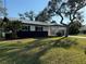 A lovely single-story home showcasing a metal roof, white exterior and a lush green lawn with trees providing shade at 128 Orange Ave, Edgewater, FL 32132