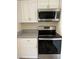 This kitchen features stainless steel appliances, including a microwave and range, with white cabinets and granite countertops at 128 Orange Ave, Edgewater, FL 32132