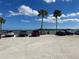 Exterior shot of a beach parking lot with multiple cars and palm trees set against a blue sky with cumulus clouds at 128 Orange Ave, Edgewater, FL 32132