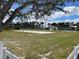 Exterior shot of a sand volleyball court in a community with a large grassy field and white picket fence at 128 Orange Ave, Edgewater, FL 32132