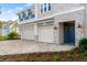 Beautiful home exterior with a three-car garage, paver driveway, stone accents, and a blue front door at 13 Arena Blanca, Ponce Inlet, FL 32127